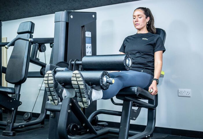 A woman uses a leg curl extension machine